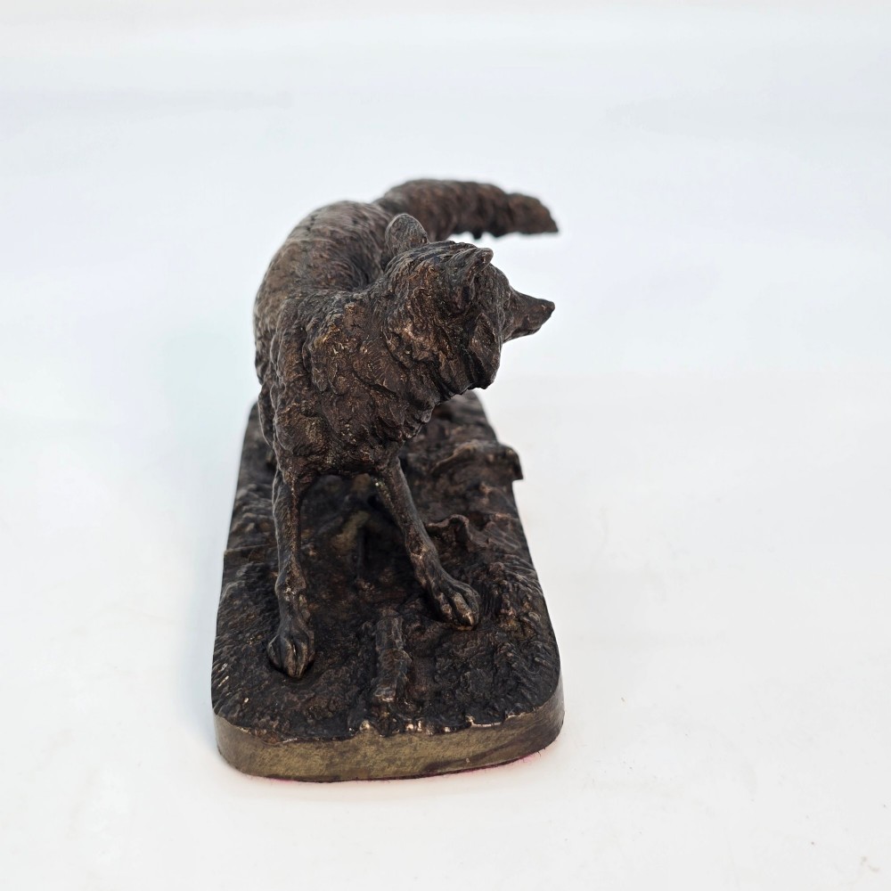 A dark brown patinated bronze sculpture depicting a crouching fox on a naturalistic textured base. View III