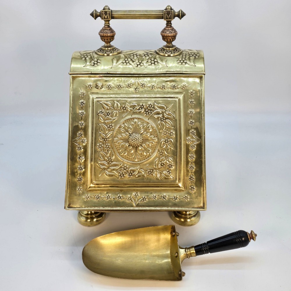 Victorian sloped brass coal box featuring repousse sunflower motifs, turned brass feet, and a top carrying handle with an integrated rear shovel. View II
