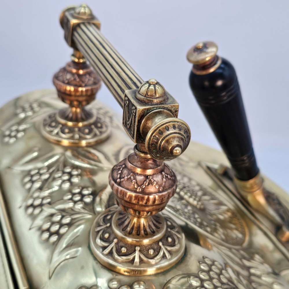 Victorian sloped brass coal box featuring repousse sunflower motifs, turned brass feet, and a top carrying handle with an integrated rear shovel. View IX