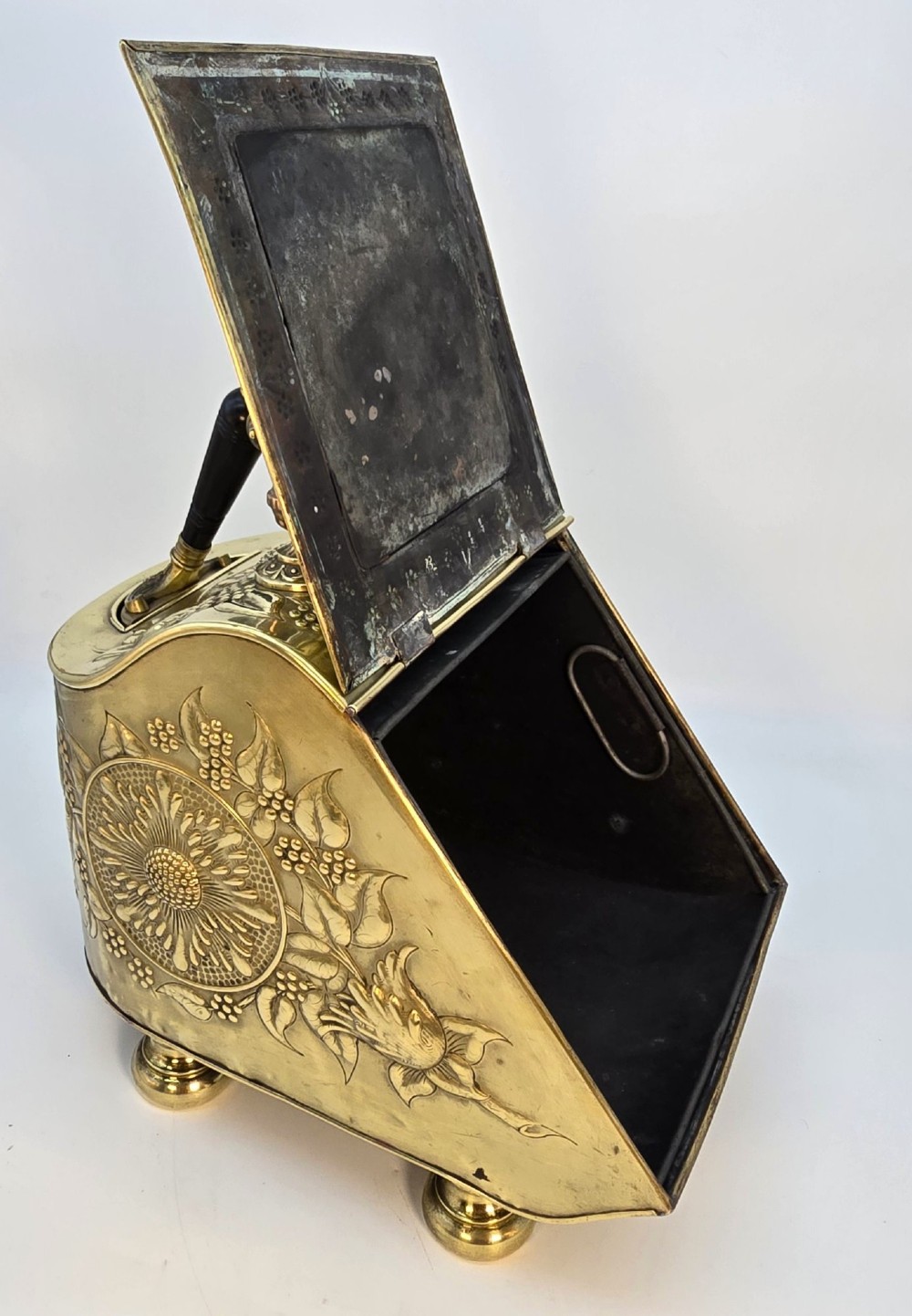 Victorian sloped brass coal box featuring repousse sunflower motifs, turned brass feet, and a top carrying handle with an integrated rear shovel. View XI