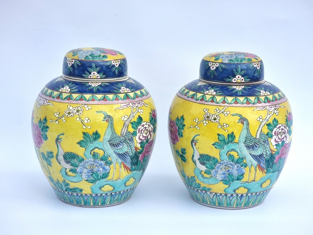 A pair of hand-painted Chinese porcelain ginger jars featuring yellow grounds decorated with pheasants and peonies, capped with blue patterned lids.