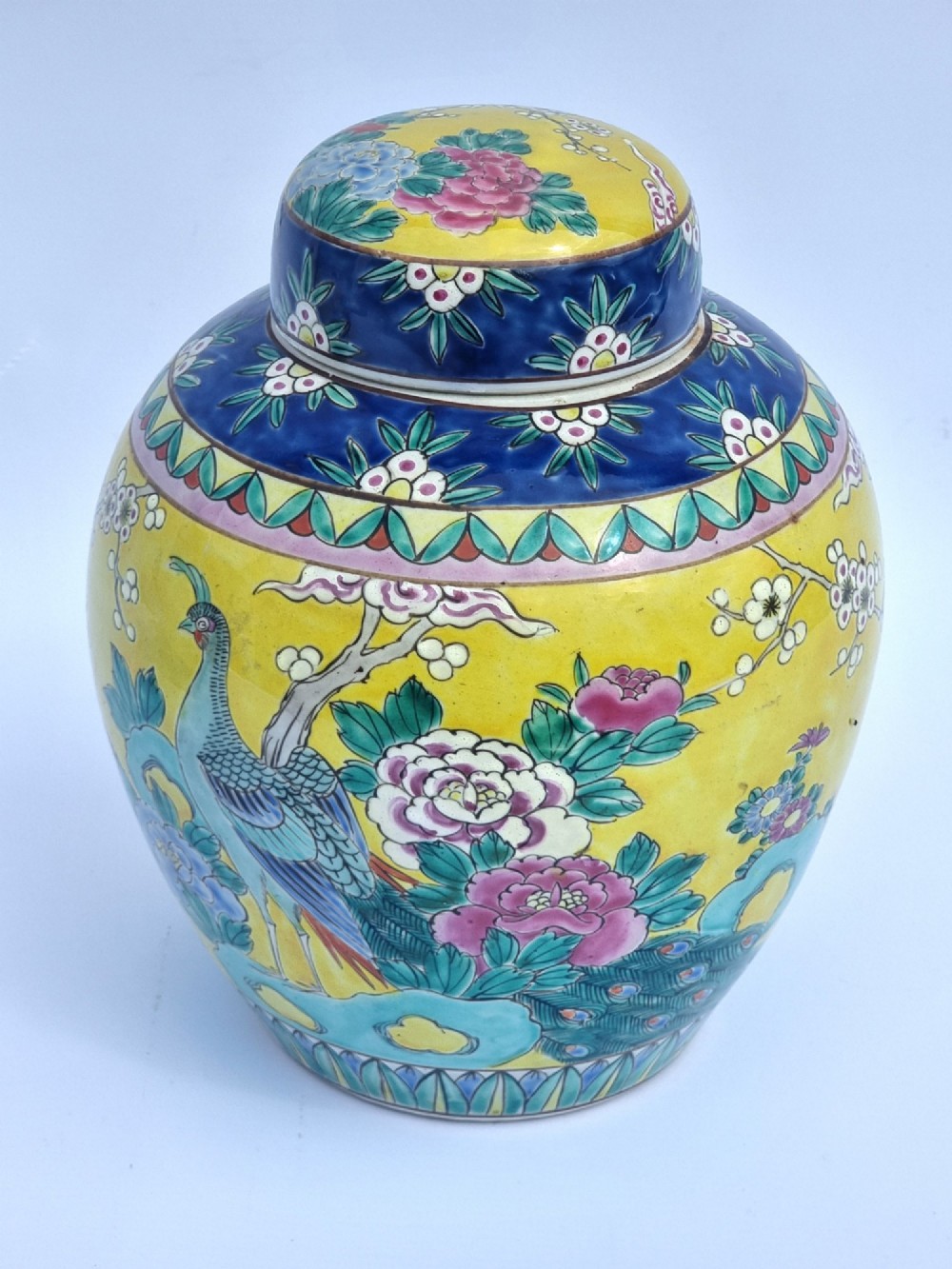 A pair of hand-painted Chinese porcelain ginger jars featuring yellow grounds decorated with pheasants and peonies, capped with blue patterned lids. View V