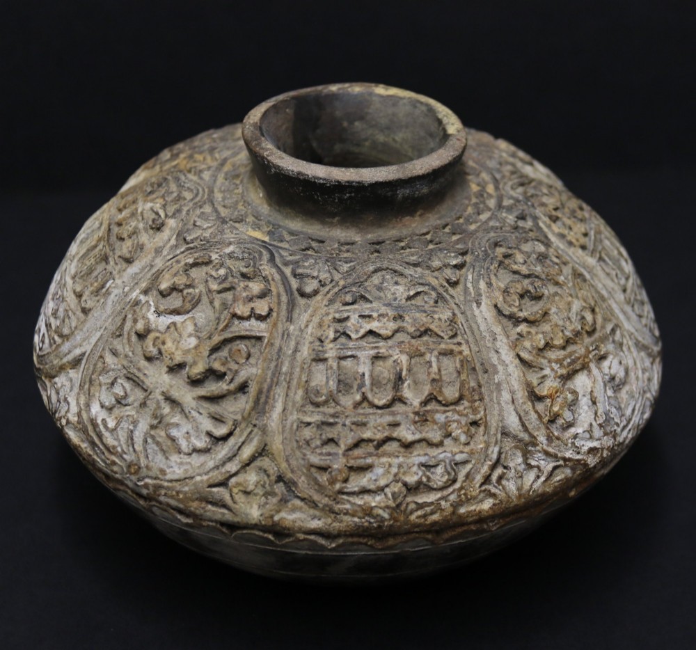 A squat rounded 17th-century Indian earthenware vase featuring deeply incised floral motifs and a low flared neck.