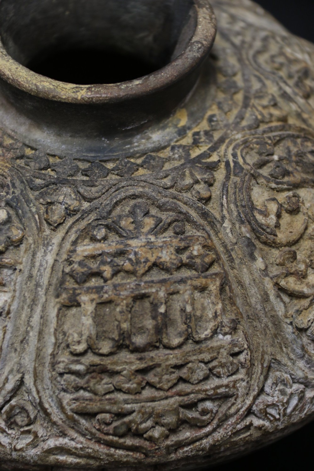 A squat rounded 17th-century Indian earthenware vase featuring deeply incised floral motifs and a low flared neck. View VII