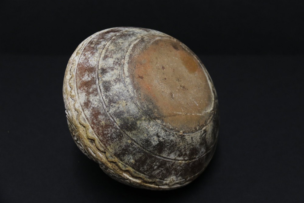 A squat rounded 17th-century Indian earthenware vase featuring deeply incised floral motifs and a low flared neck. View IX