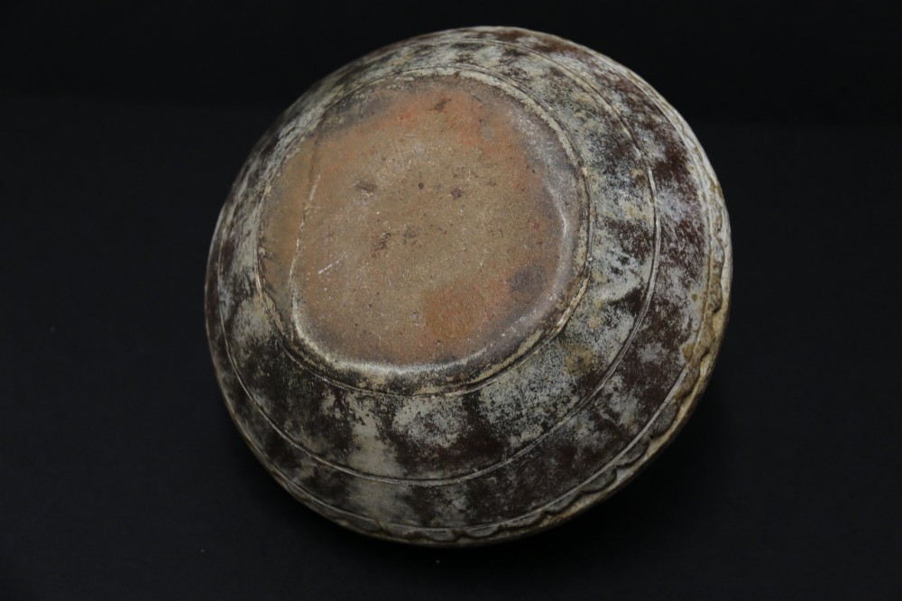 A squat rounded 17th-century Indian earthenware vase featuring deeply incised floral motifs and a low flared neck. View X