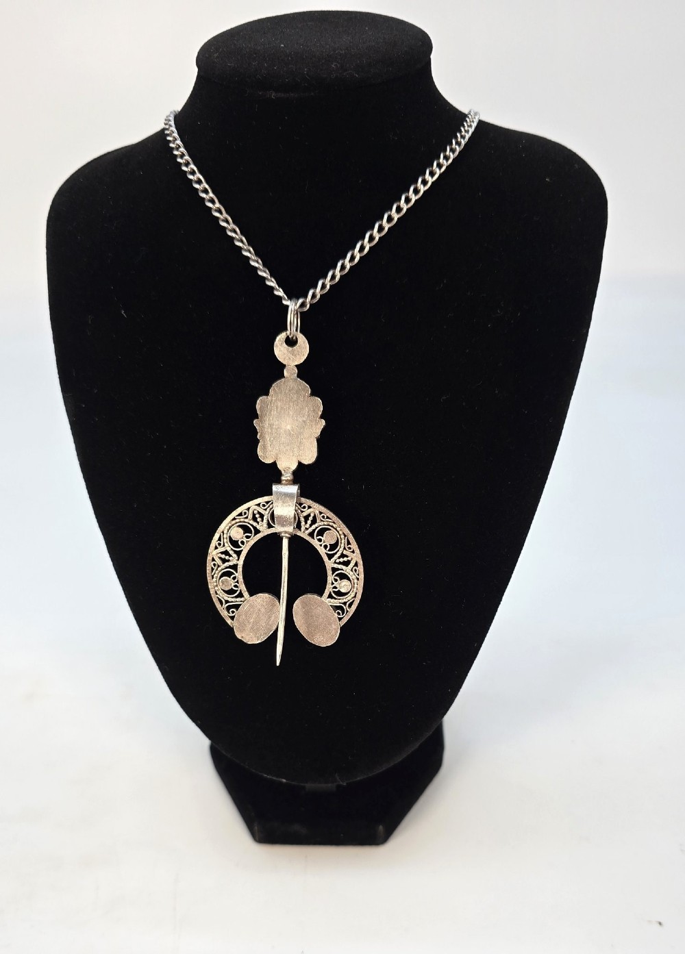 An antique silver filigree pendant featuring red and blue cabochon stones suspended on a silver curb chain. View V