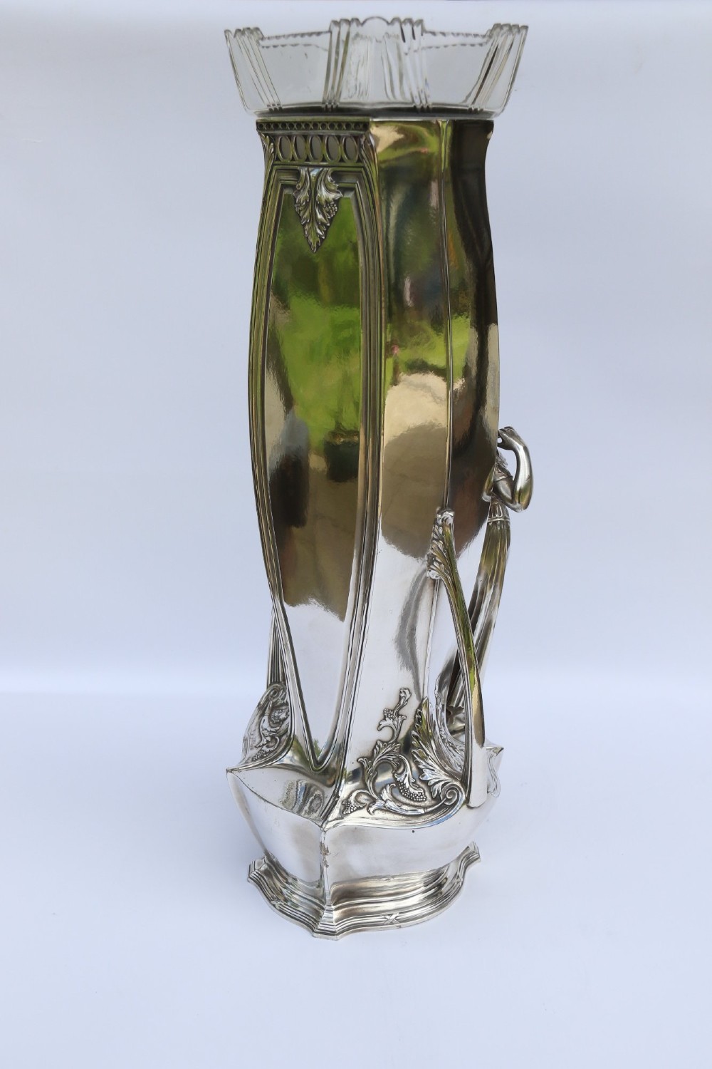 A tall silver-plated Art Nouveau vase featuring a relief figure of a maiden holding flowers, twin handles, an engraved presentation inscription at the base, and a clear glass liner. View XI