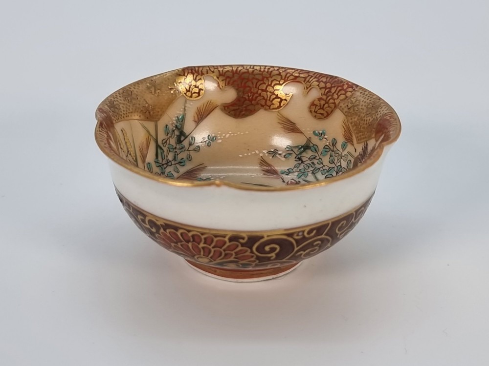 A pair of small, round Japanese porcelain bowls featuring intricate floral painted interiors and detailed red and gold geometric borders around scalloped rims. View IV