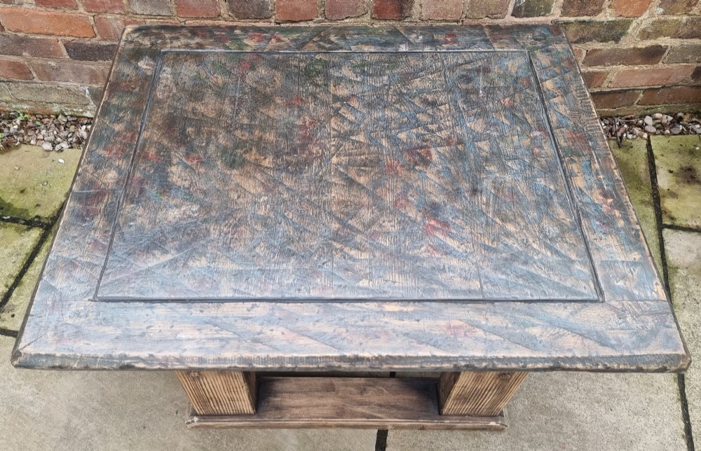 A low rectangular rustic oak table featuring a heavily distressed painted top with linear detailing supported by thick trestle legs. View III