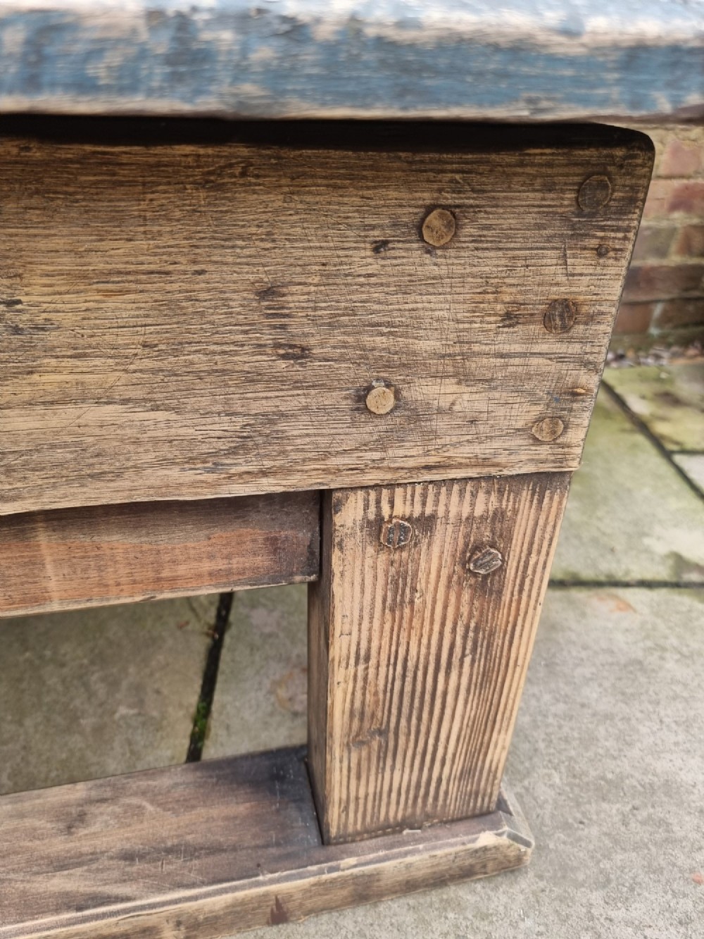 A low rectangular rustic oak table featuring a heavily distressed painted top with linear detailing supported by thick trestle legs. View VII