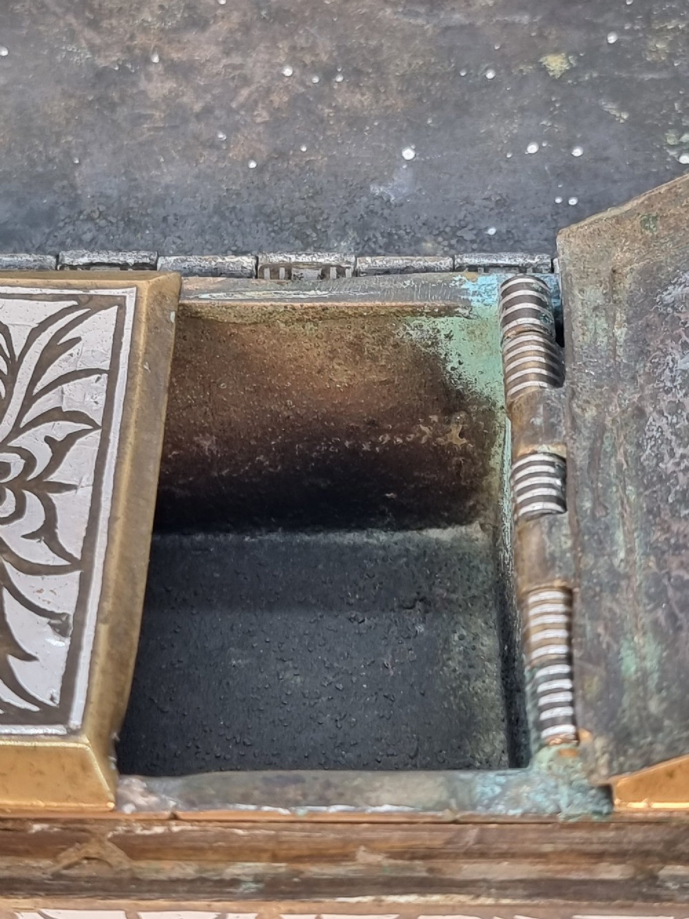 A rectangular dark bronze betel box embellished with detailed silver floral scrollwork inlay and featuring side handles. View IX