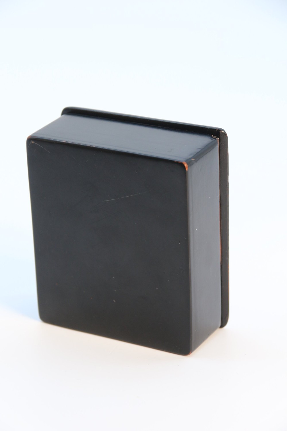 A rectangular black lacquered box featuring a hand-painted portrait of a young woman with a red ribbon in her hair on the top lid. View VIII