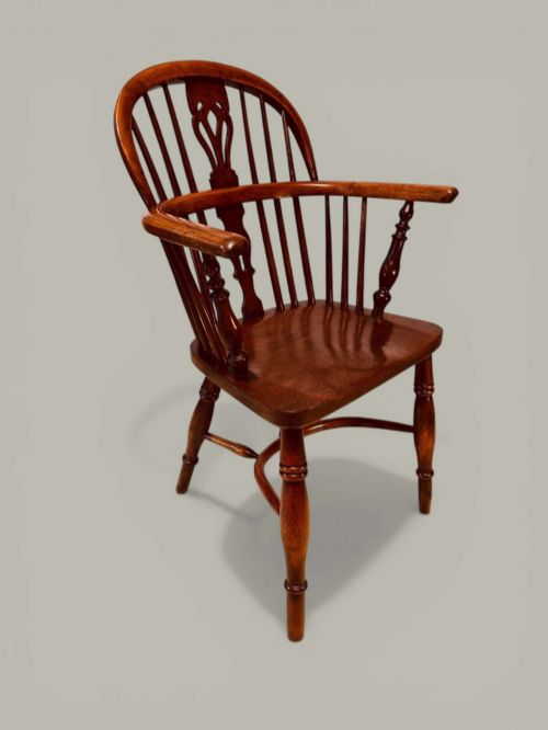 fig 1. A mid-19th-century Windsor armchair crafted from polished yew and elm wood, featuring a hoop back, a pierced central splat, swept arms, and turned legs.