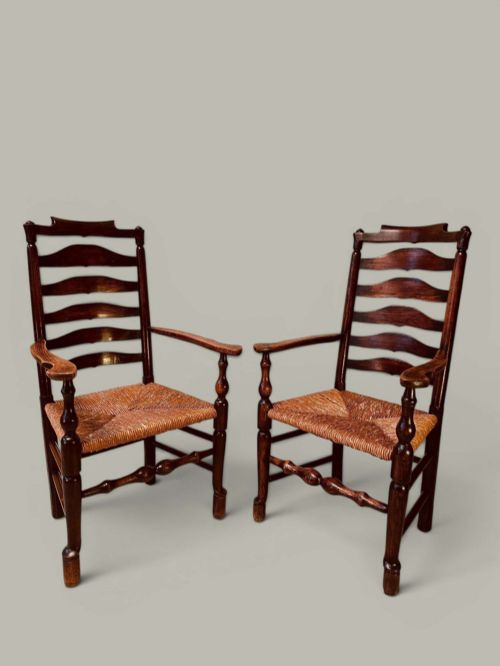 fig 2. A set of dark brown ladder back dining chairs featuring woven rush seats, curved horizontal slats, and turned stretcher rails.