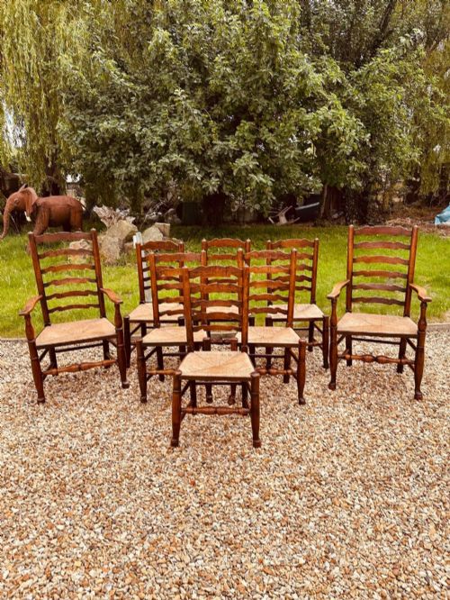 fig 1. A set of eight antique ash dining chairs featuring wavy ladder backs, turned stretchers, and woven rush seats, comprising six side chairs and two carver armchairs.