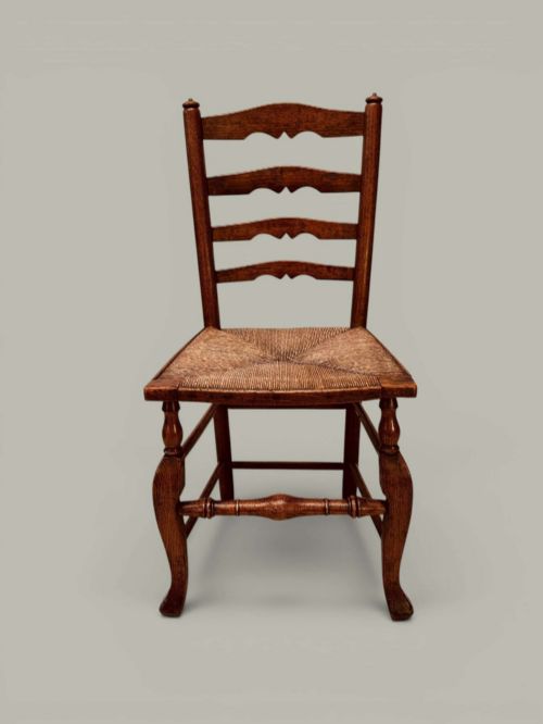 fig 1. A pair of antique ash ladder back side chairs featuring shaped back rungs, woven rush seats, cabriole front legs, and turned stretchers.