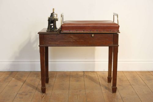 fig 1. An Edwardian oak jockey scale featuring a padded brown leather seat with brass studs, brass side handles, and an integrated metal balance beam weighing mechanism.