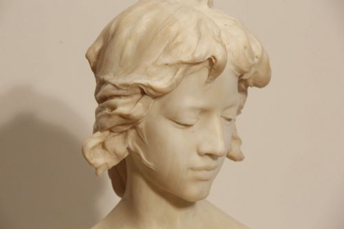 fig 3. An early twentieth-century carved Carrara marble bust depicting a young female subject with a carved floral corsage, mounted on a wooden pedestal base.