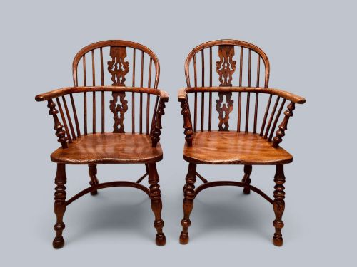 fig 1. A pair of 19th-century yew wood Windsor armchairs featuring low hoop backs, pierced central splats, turned spindle supports, and shaped seats.