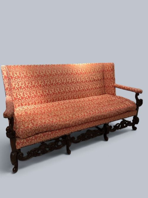 fig 1. Late 19th-century Louis XIV style walnut sofa with intricately carved stretchers and red patterned damask fabric.
