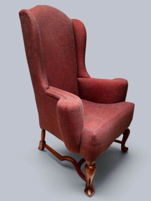 fig 1. A high-backed Queen Anne style wing armchair upholstered in burgundy textured fabric with walnut cabriole front legs and curved stretchers.