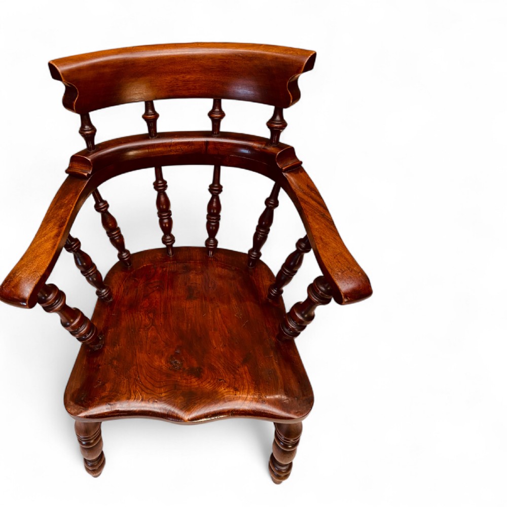 A set of sixteen matching comb back wooden Windsor armchairs made from brown ash and alder wood featuring turned spindles and shaped crest rails. View V
