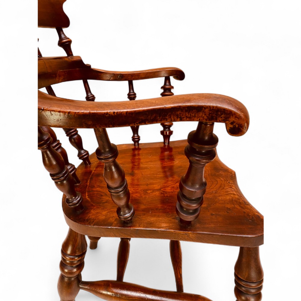A set of sixteen matching comb back wooden Windsor armchairs made from brown ash and alder wood featuring turned spindles and shaped crest rails. View VII