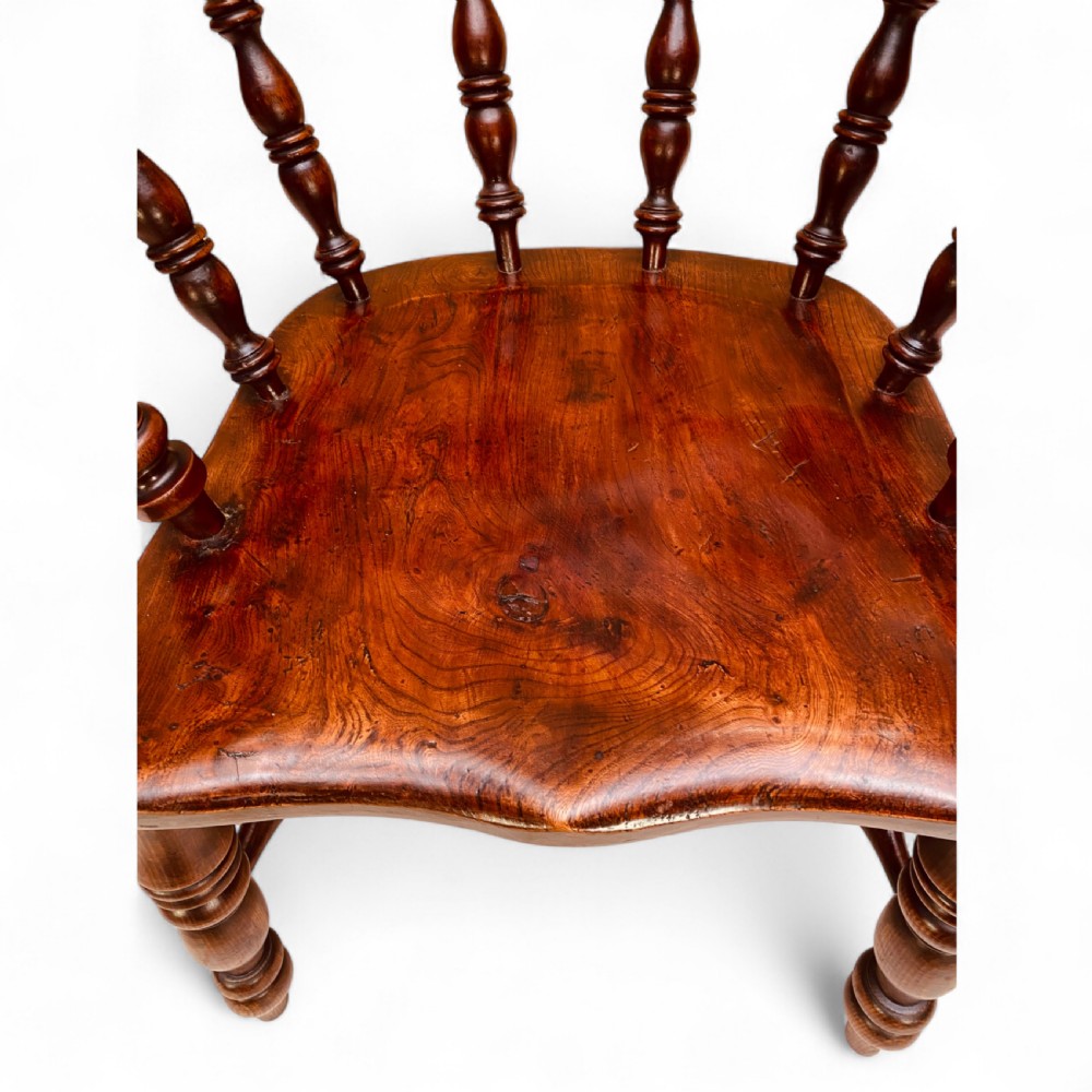 A set of sixteen matching comb back wooden Windsor armchairs made from brown ash and alder wood featuring turned spindles and shaped crest rails. View IX