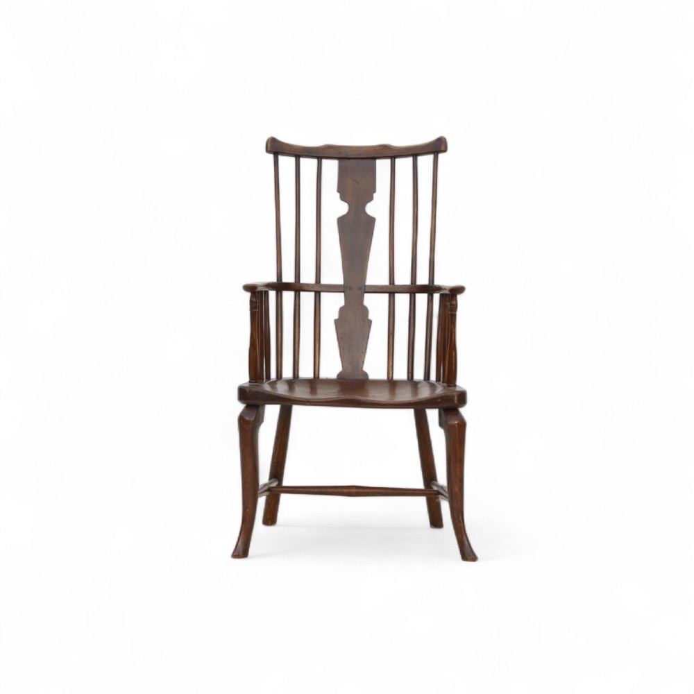 An 18th-century dark brown comb-back Windsor armchair made of ash and elm, featuring a high spindle back, central shaped splat, curved arms, and turned legs. View IV