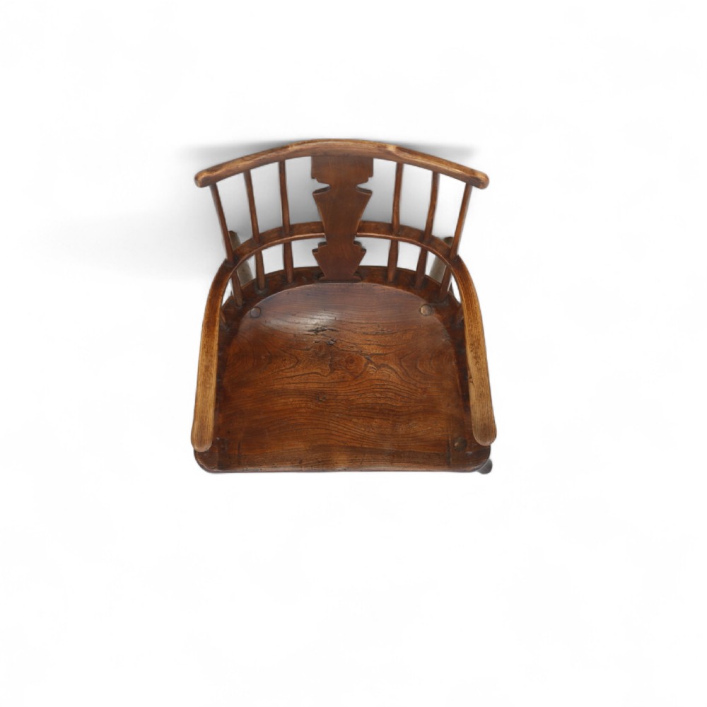 An 18th-century dark brown comb-back Windsor armchair made of ash and elm, featuring a high spindle back, central shaped splat, curved arms, and turned legs. View VIII