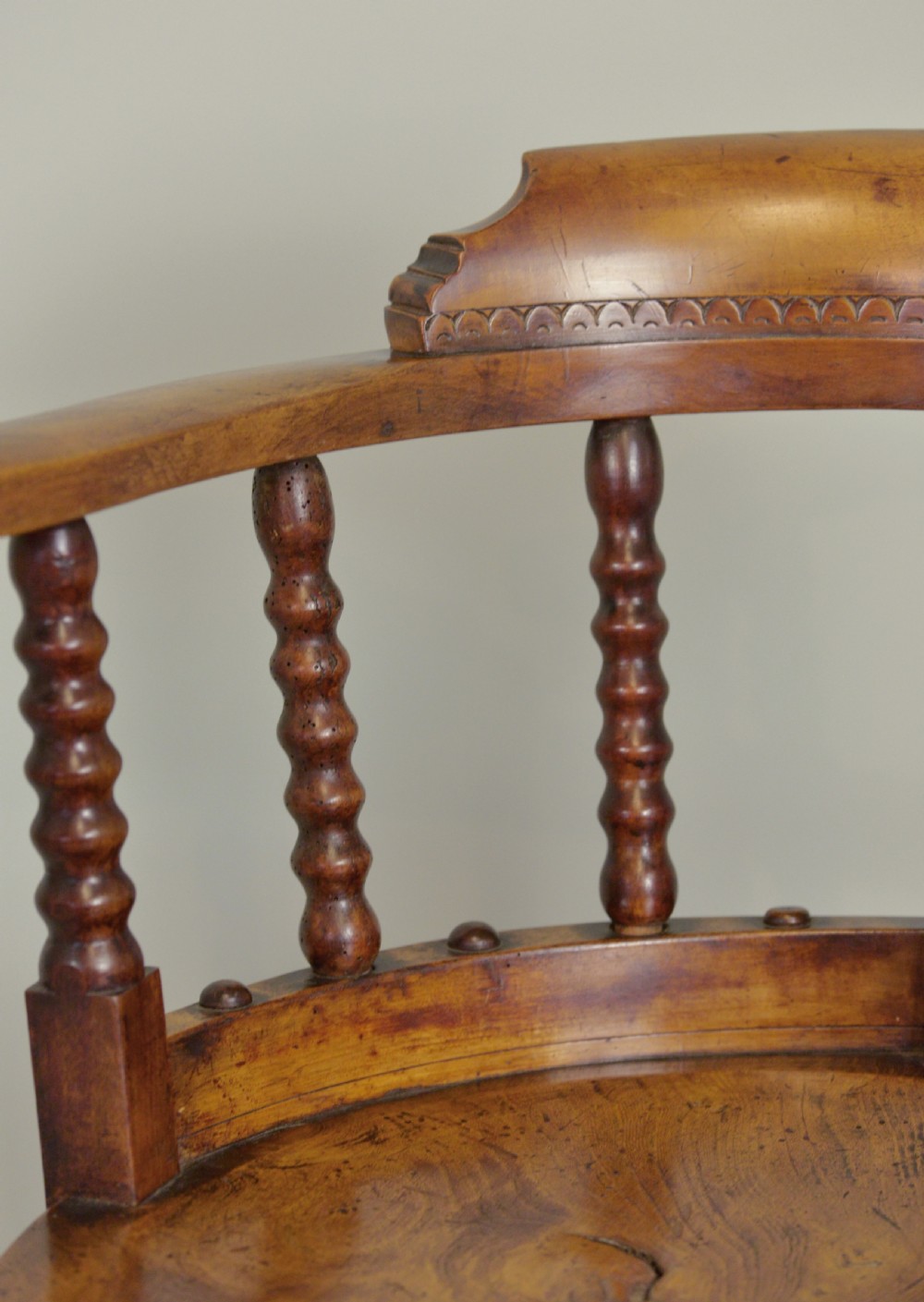 A set of six Victorian wooden captains armchairs featuring low curved backs, spindle supports, round solid seats, and turned legs. View IV