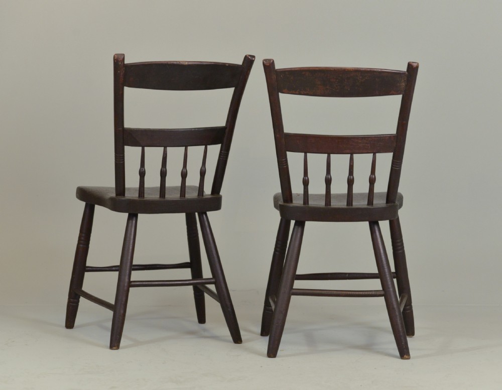 A pair of dark brown 19th-century American slat back wooden kitchen chairs featuring turned legs and back spindles. View II