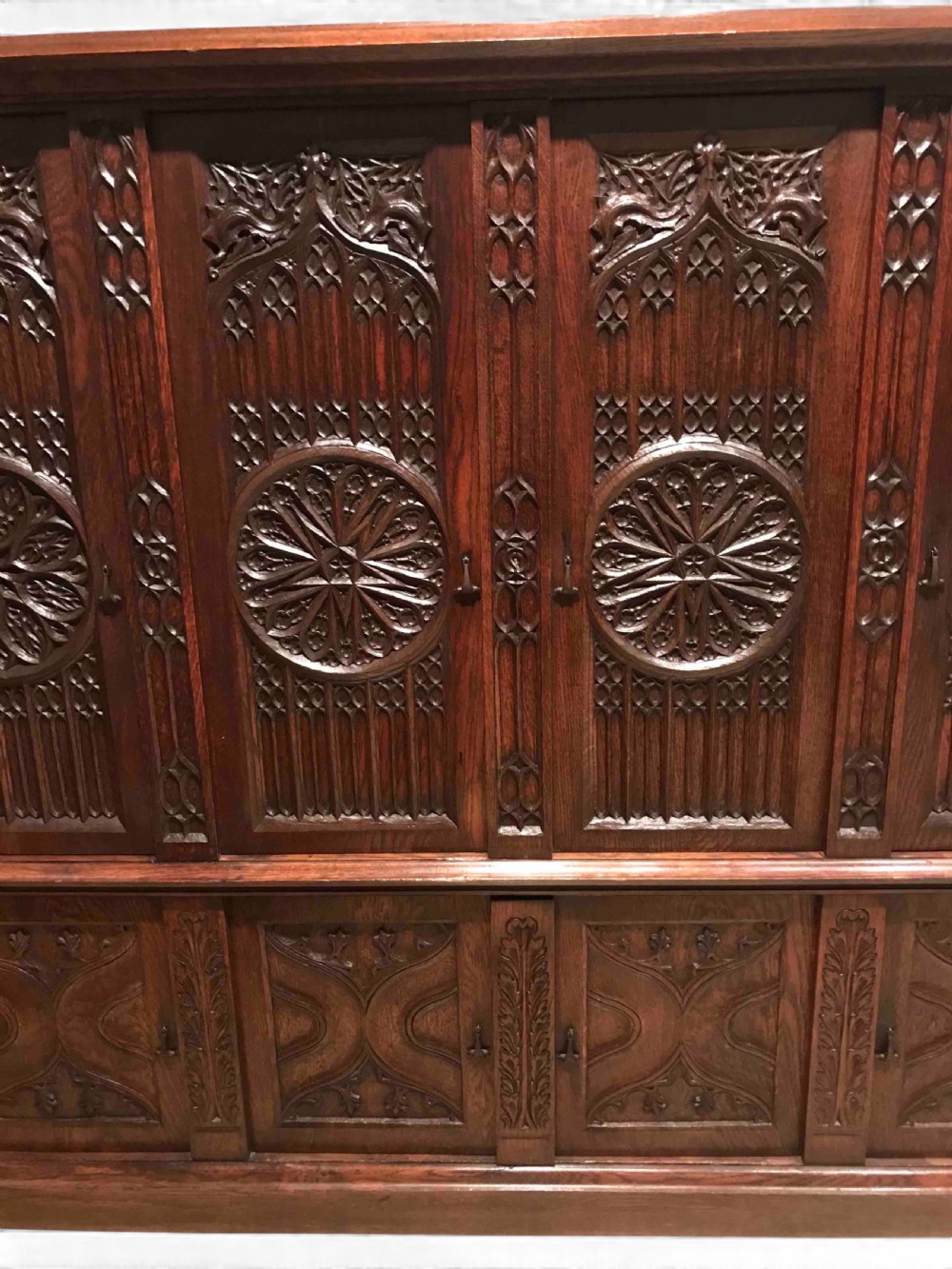 A large dark oak Gothic Revival cupboard featuring carved tracery panels, rose window motifs, and lower cabinet doors. View III