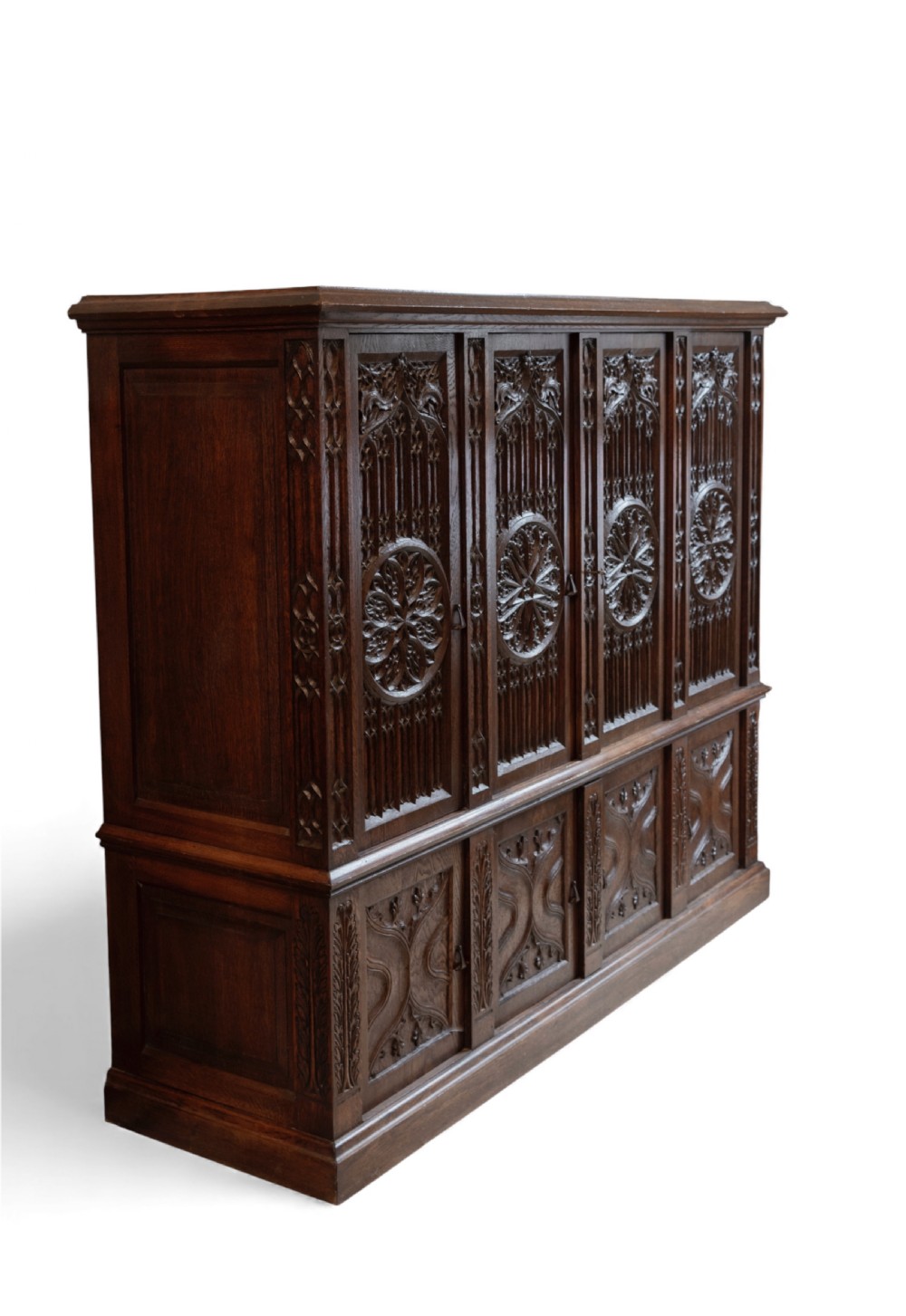 A large dark oak Gothic Revival cupboard featuring carved tracery panels, rose window motifs, and lower cabinet doors. View VI