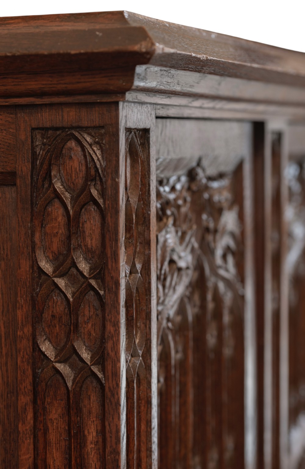 A large dark oak Gothic Revival cupboard featuring carved tracery panels, rose window motifs, and lower cabinet doors. View VII