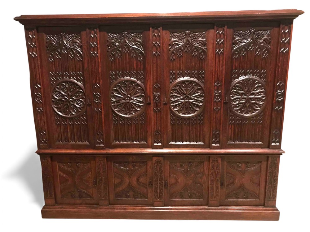 A large dark oak Gothic Revival cupboard featuring carved tracery panels, rose window motifs, and lower cabinet doors. View X