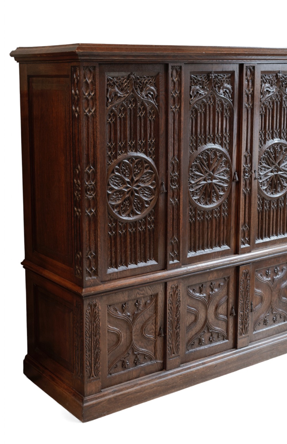A large dark oak Gothic Revival cupboard featuring carved tracery panels, rose window motifs, and lower cabinet doors. View XI