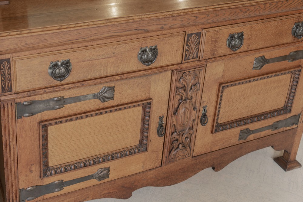 An antique Art Nouveau oak dresser featuring a mirrored upper tier with carved accents and a lower cabinet base with iron hardware. View IV