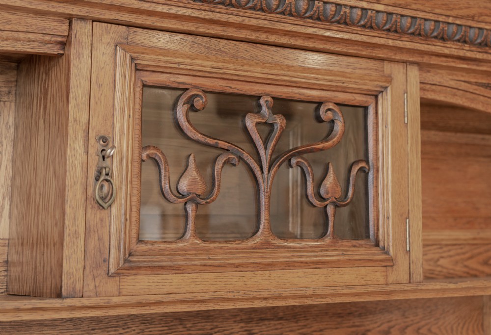 An antique Art Nouveau oak dresser featuring a mirrored upper tier with carved accents and a lower cabinet base with iron hardware. View VI