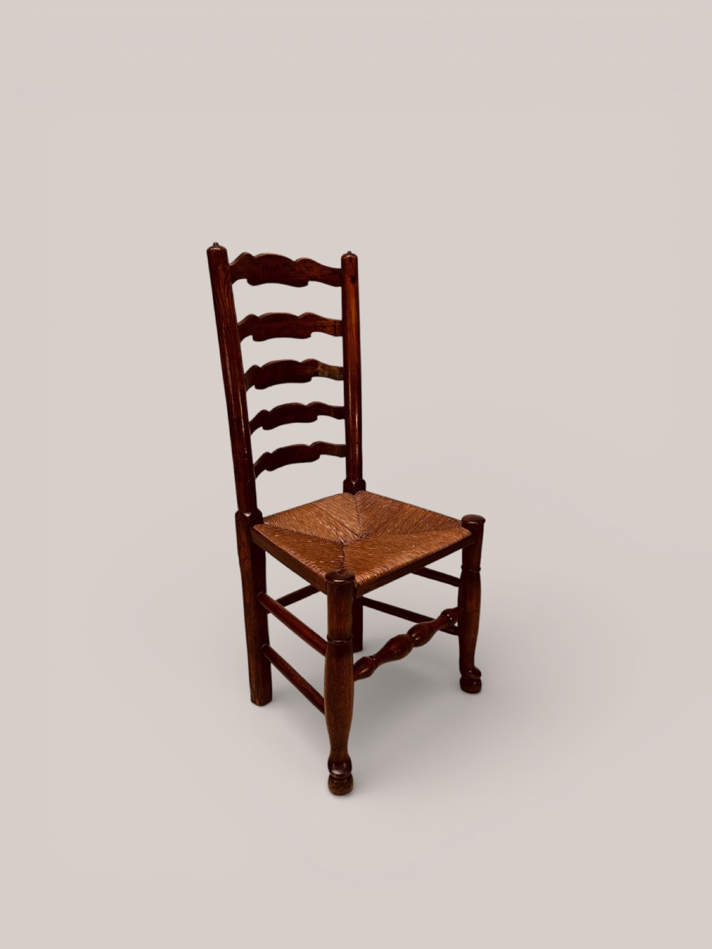 A pair of dark ash carver dining chairs featuring shaped wavy ladderback slats, turned front legs, and woven rush seats. View V