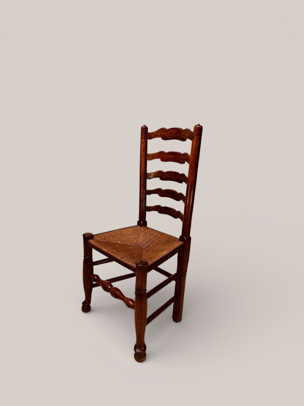 A pair of dark ash carver dining chairs featuring shaped wavy ladderback slats, turned front legs, and woven rush seats. View VI
