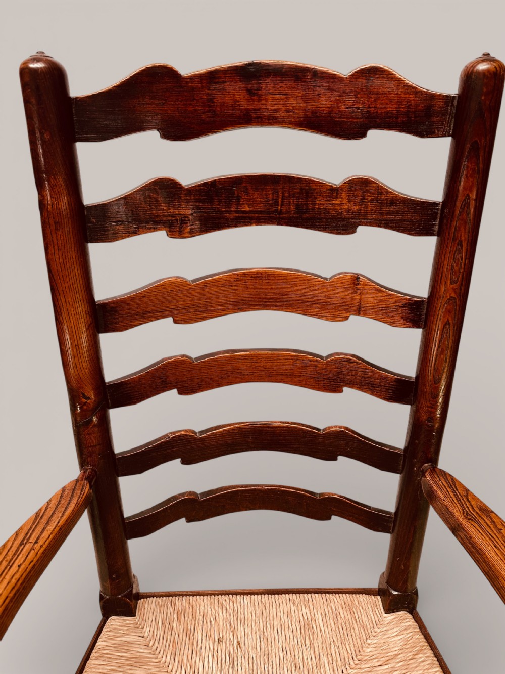 A pair of dark ash carver dining chairs featuring shaped wavy ladderback slats, turned front legs, and woven rush seats. View VIII