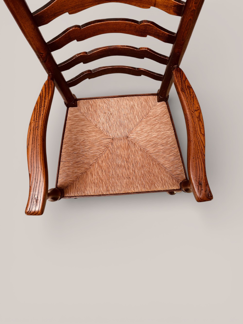 A pair of dark ash carver dining chairs featuring shaped wavy ladderback slats, turned front legs, and woven rush seats. View XIII
