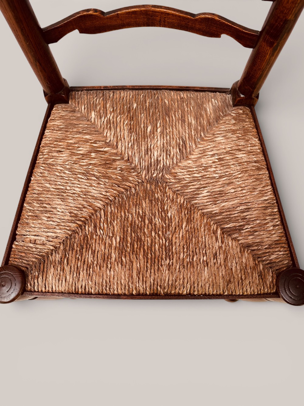 A pair of dark ash carver dining chairs featuring shaped wavy ladderback slats, turned front legs, and woven rush seats. View XIV