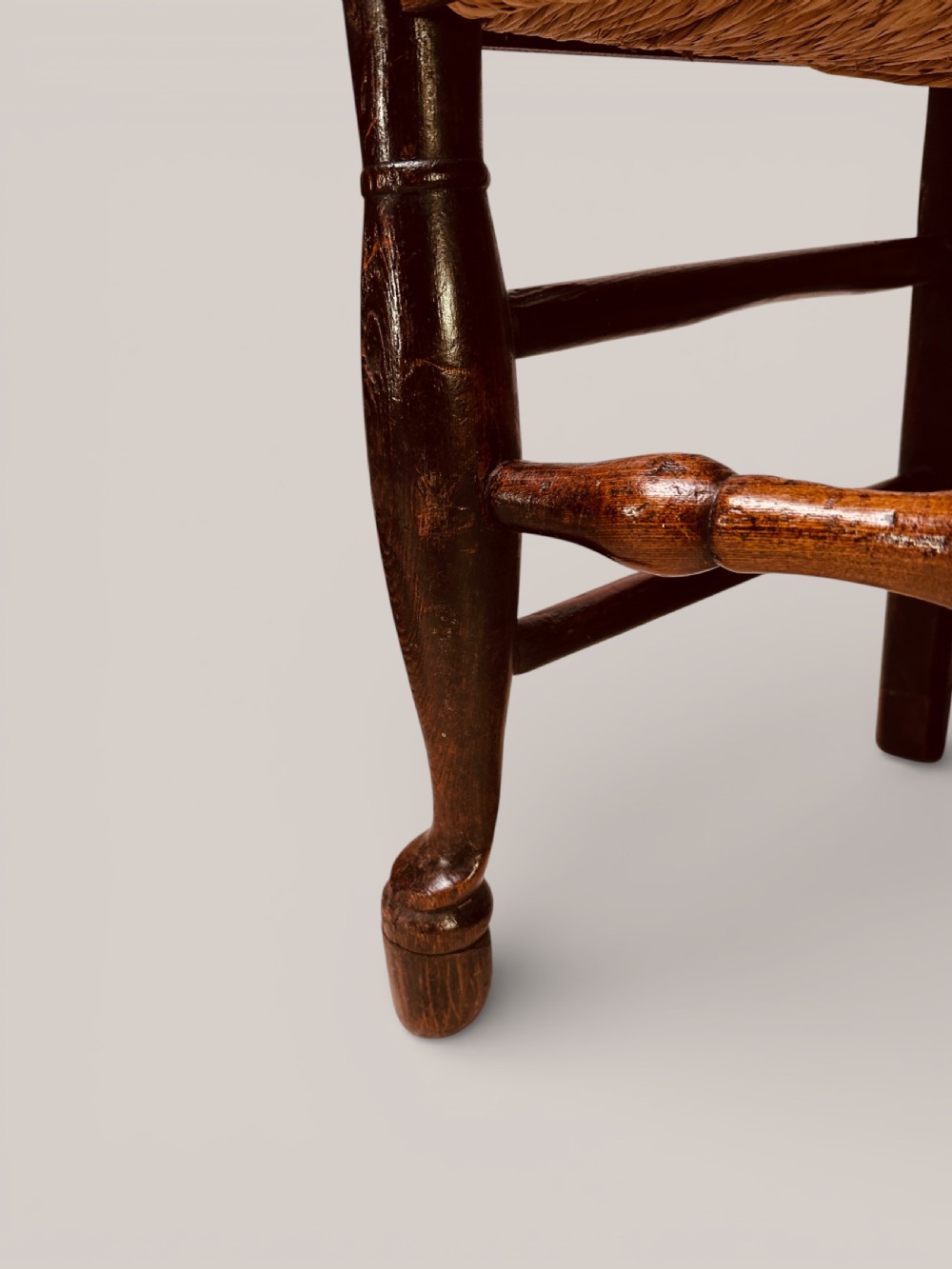 A pair of dark ash carver dining chairs featuring shaped wavy ladderback slats, turned front legs, and woven rush seats. View XV