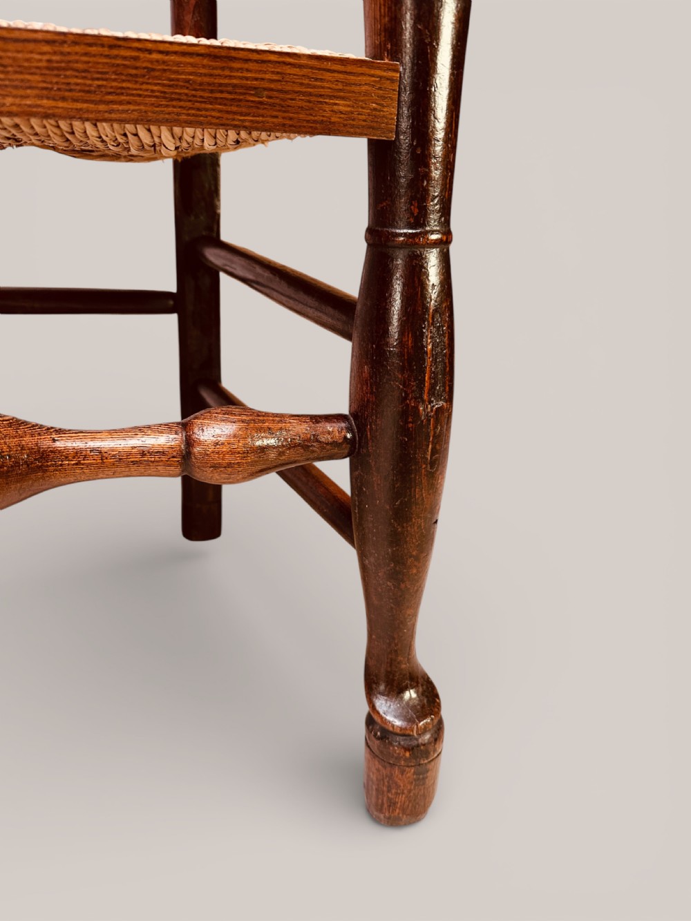 A pair of dark ash carver dining chairs featuring shaped wavy ladderback slats, turned front legs, and woven rush seats. View XVI