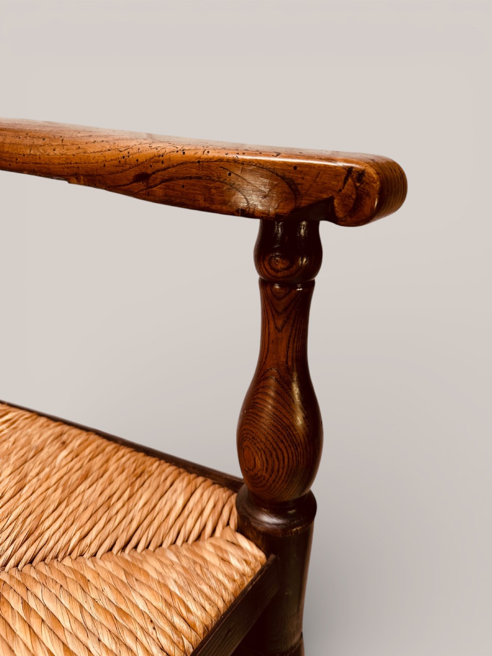 A pair of dark ash carver dining chairs featuring shaped wavy ladderback slats, turned front legs, and woven rush seats. View XVII
