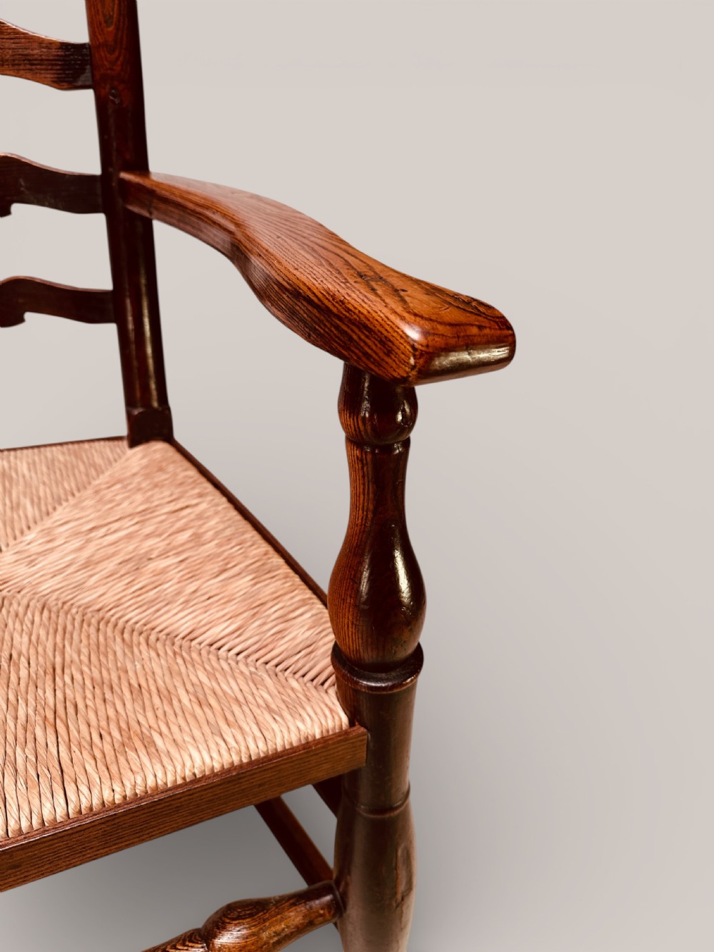 A pair of dark ash carver dining chairs featuring shaped wavy ladderback slats, turned front legs, and woven rush seats. View XVIII