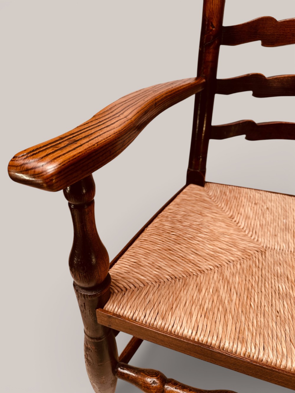 A pair of dark ash carver dining chairs featuring shaped wavy ladderback slats, turned front legs, and woven rush seats. View XIX